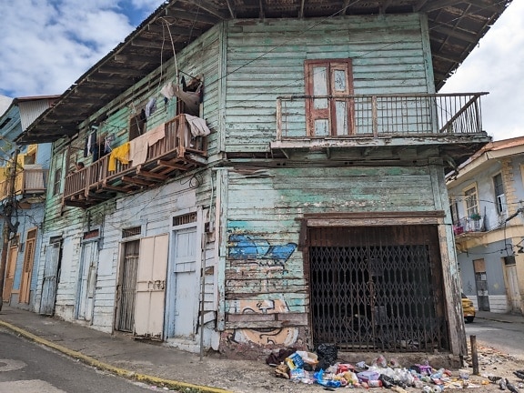 Rumah bobrok dengan sampah di depannya di sudut jalan di bagian kota yang miskin