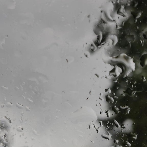 Trama nebbiosa in bianco e nero di gocce d’acqua su vetro trasparente