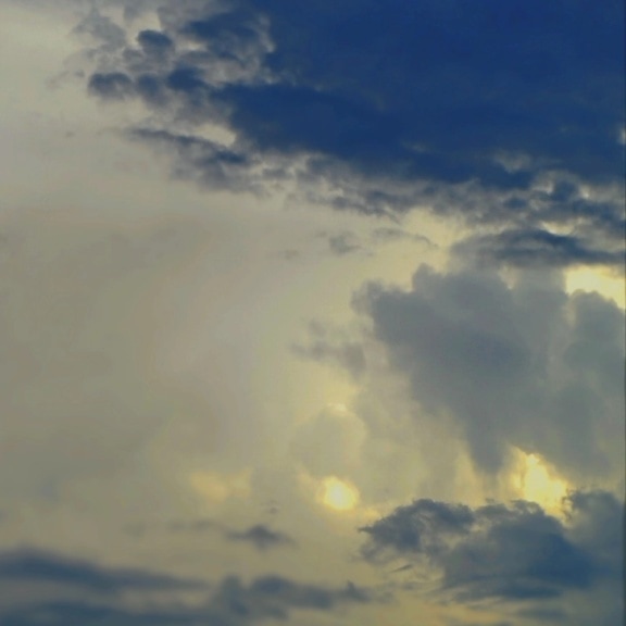 Tummansinisiä pilviä auringon takana