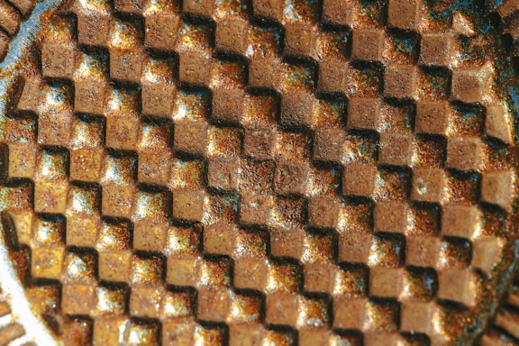 Superficie metálica oxidada con patrón geométrico cuadrado