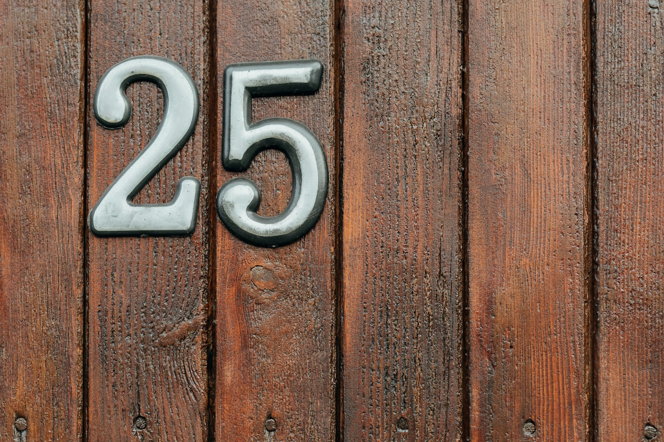 Casa numărul 25 pe o ușă din lemn vopsită în maro