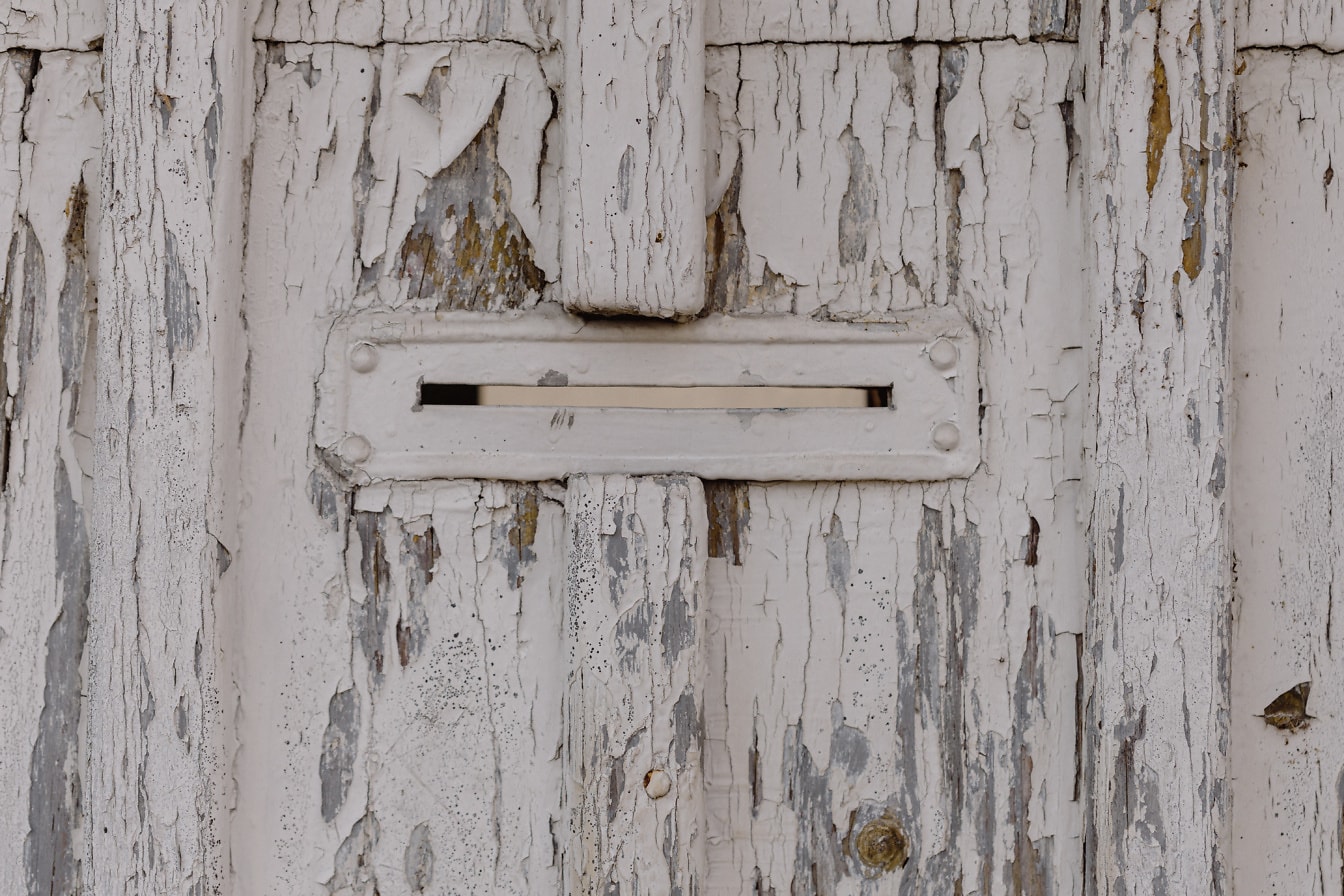 흰색 페인트가 벗겨진 오래된 나무 문에 우편물 슬롯