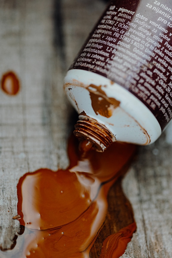 Pintura acrílica marrón derramada de una botella de plástico