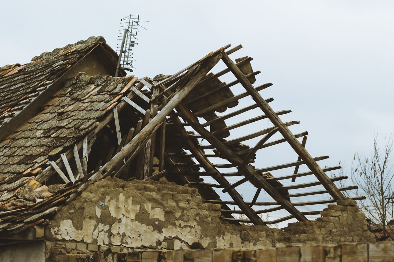 Atap rumah tua yang rusak dengan dinding batu bata yang terbuat dari tanah