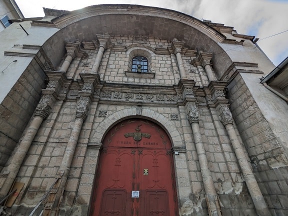Entrance to the church of the virgin Carmen with a red entrance door made of cast iron