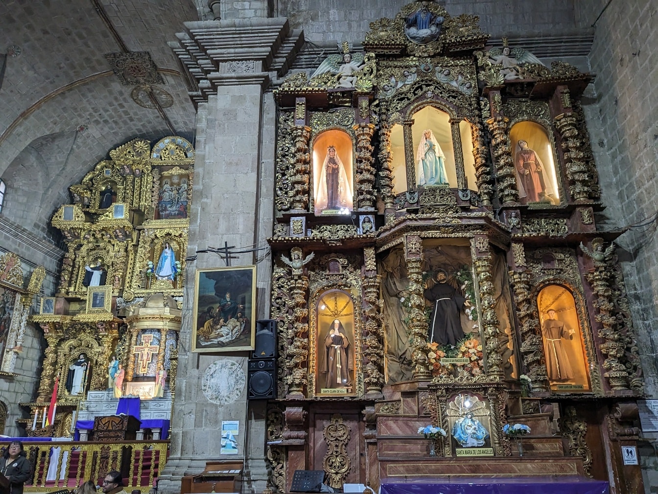 Binnenland van kerk met verfraaid altaar met beelden van heiligen in traditionele Latijns-Amerikaanse stijl