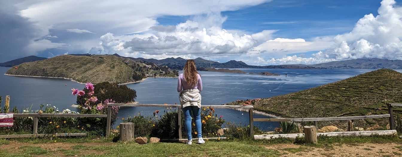Mujer de pie en un mirador en la cima de la colina y disfrutando de un paisaje majestuoso