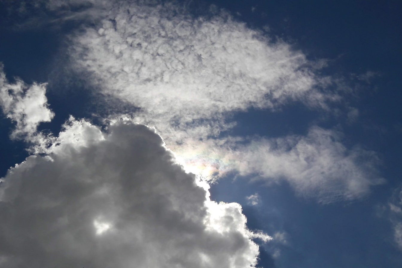 雲の切れ間から差し込む太陽の光が差し込む青空に、白い雲の向こうの太陽