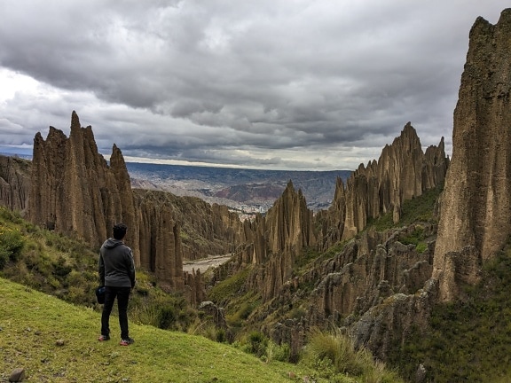 Homem de pé em uma colina olhando para altas formações rochosas no vale das almas
