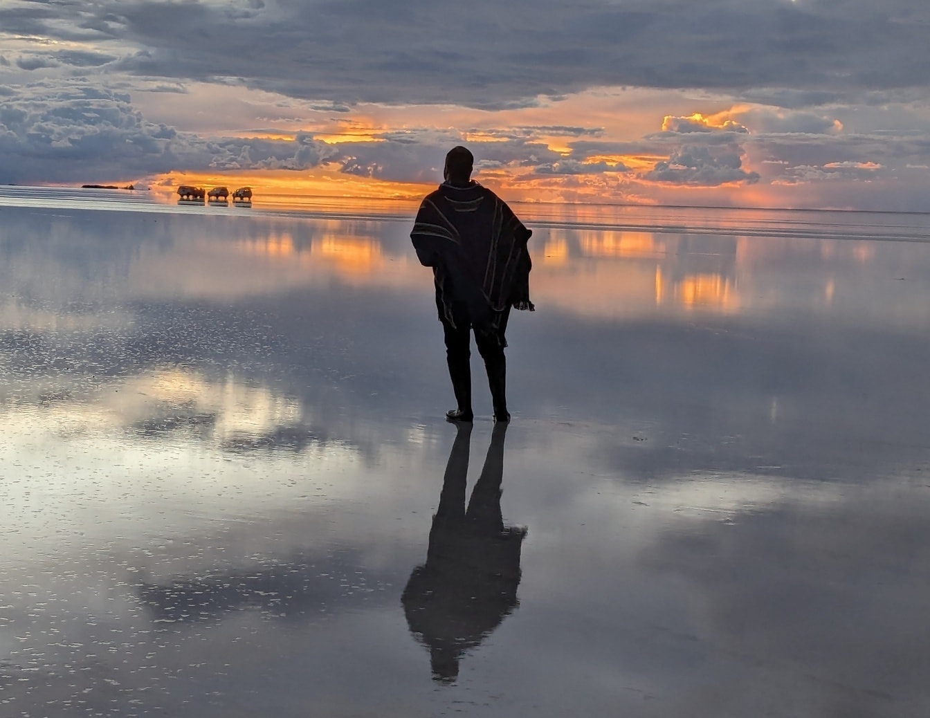 Om stând pe o apă cu un apus de soare frumos în fundal, reflectând pe o suprafață de apă
