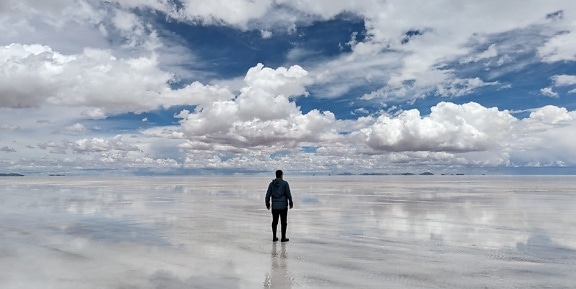 Salt lake landscape with man standing on a water in Uyuni natural park in Bolivia