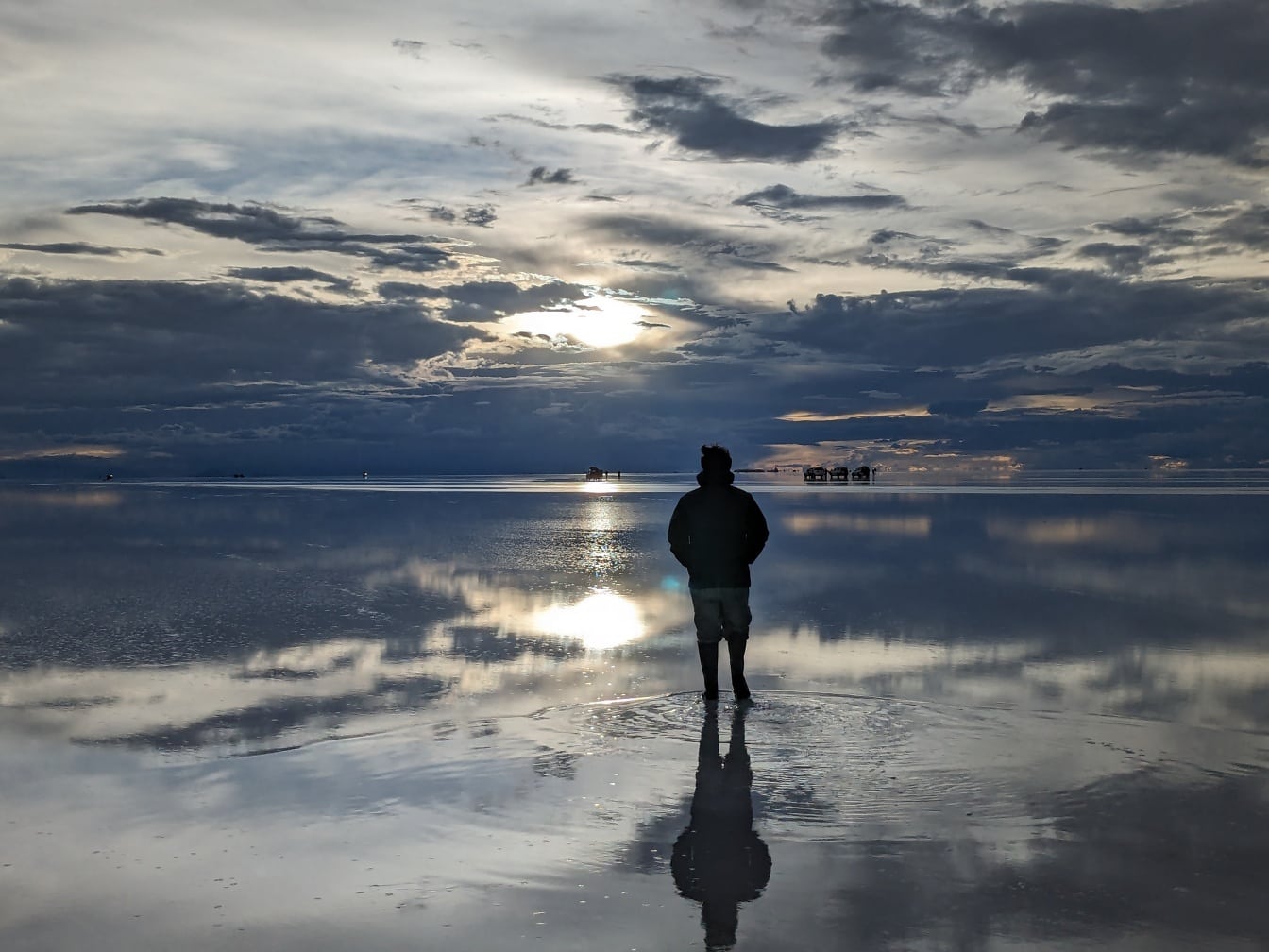 Silhouette of man standing in shallow water at dusk