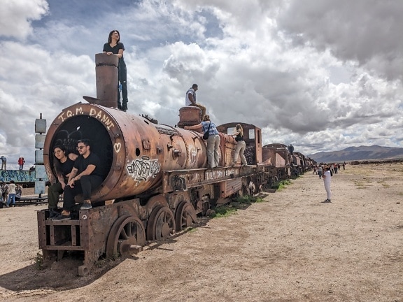 Turistas em um trem enferrujado abandonado no deserto em um lugar conhecido como cemitério de trens