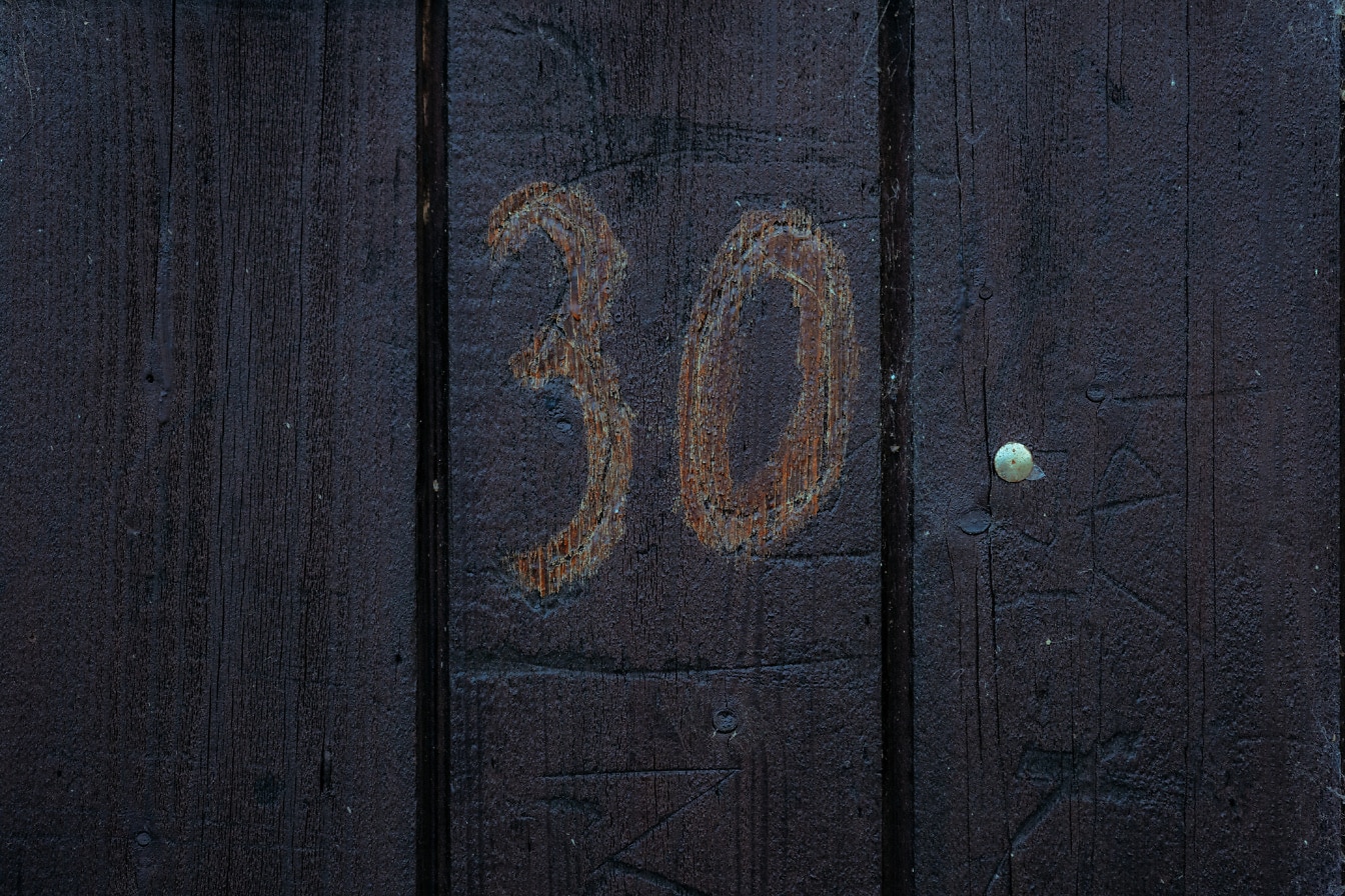 Nummer 30 på lodrette træplanker malet i mørkebrun farve