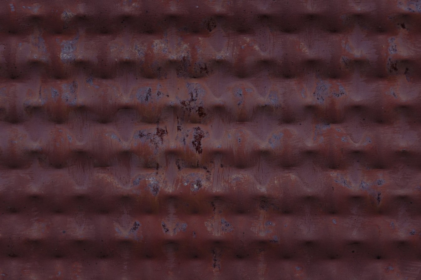 Rostige Metalloberfläche mit geometrischem Muster, lackiert mit verblasster roter Farbe