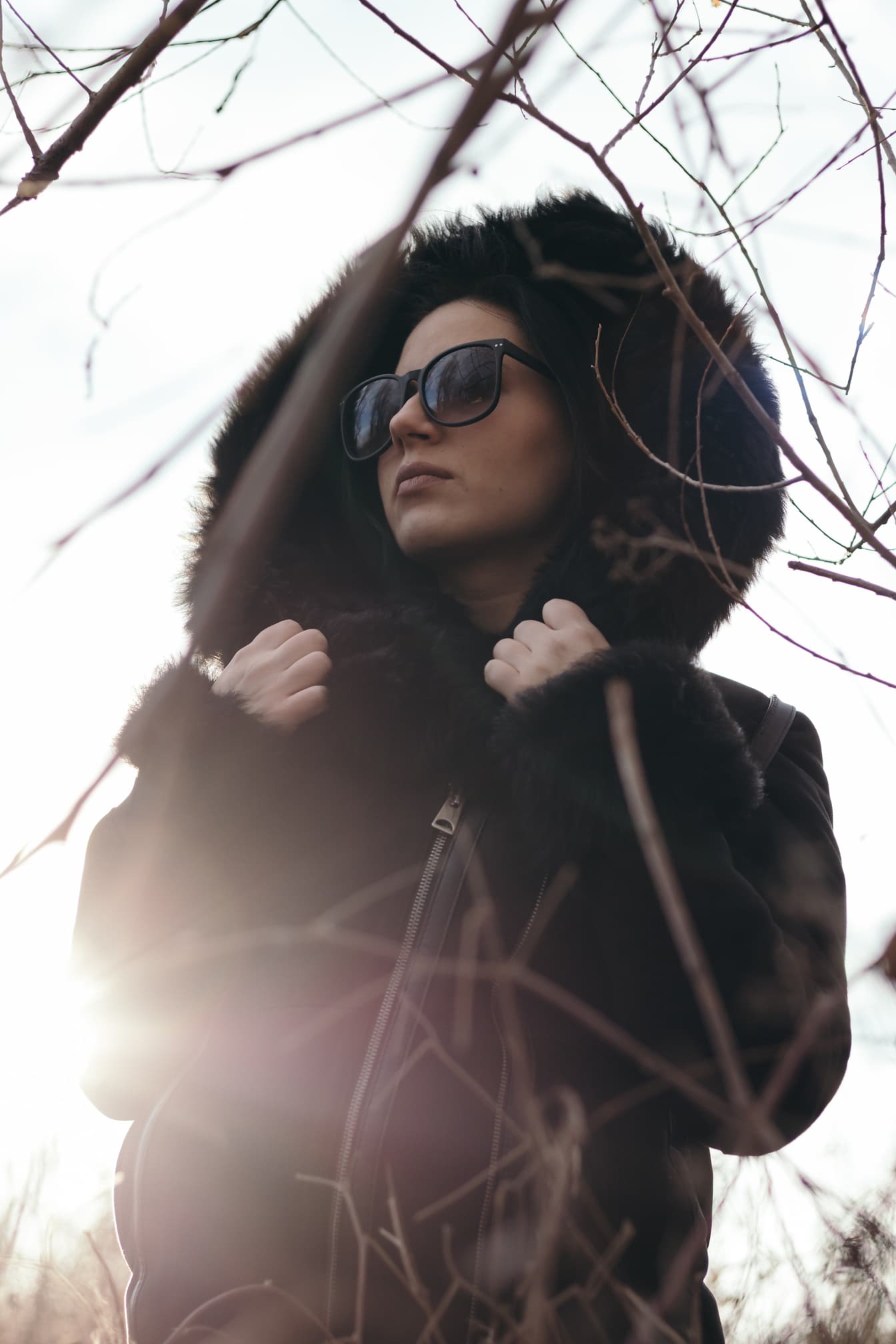 Portræt af kvinde iført solbriller og en sort frakke med hætte