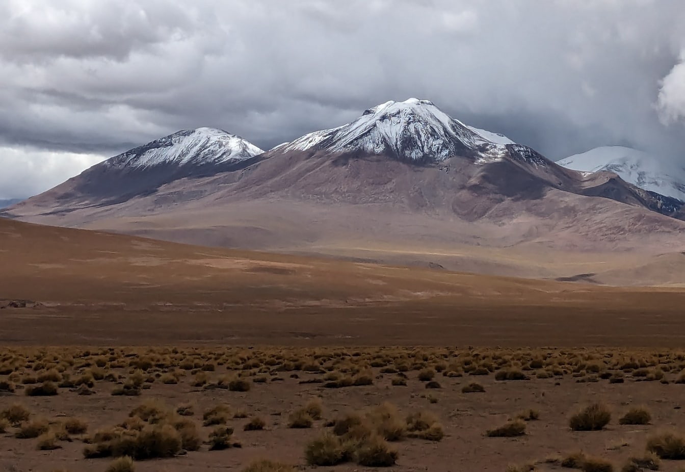 Krajina so zasneženými vrcholmi a mrakmi v púšti Atacama v Južnej Amerike