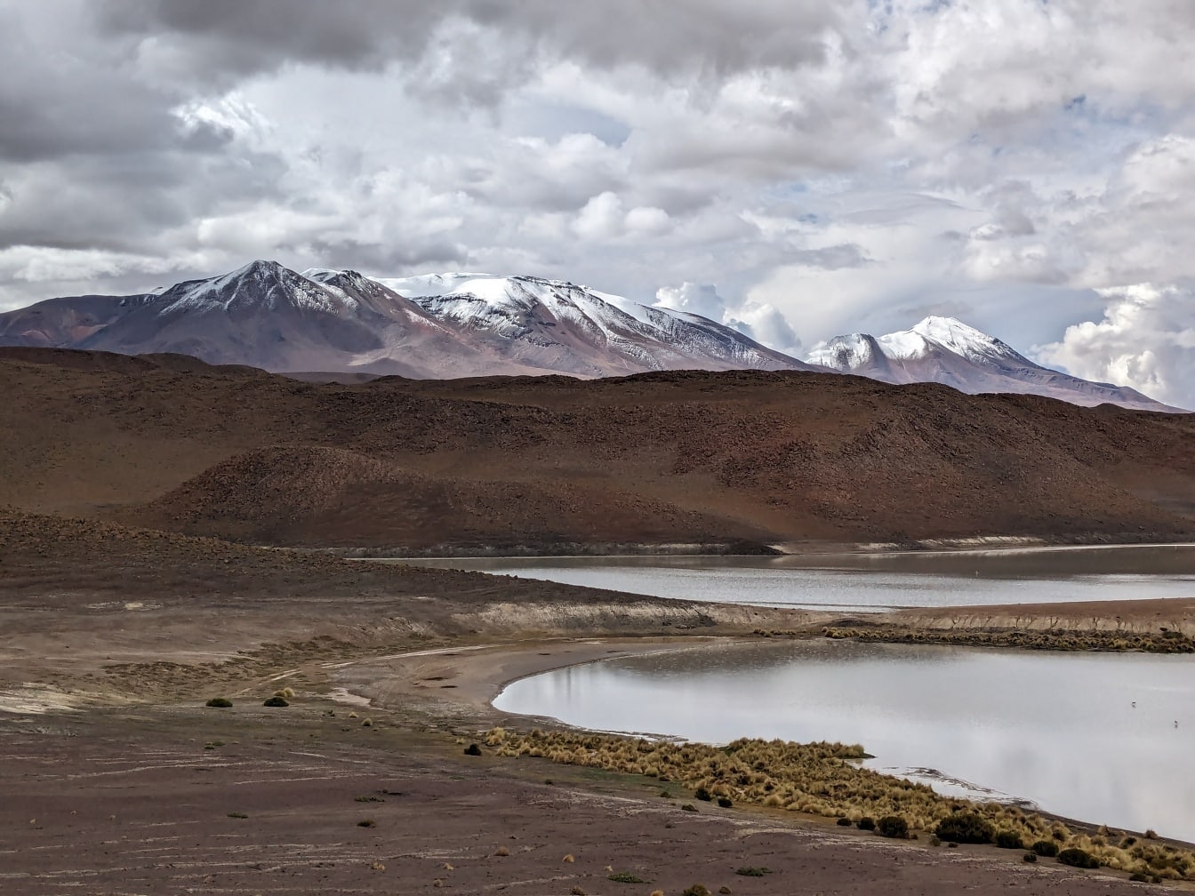Sø i en Salar de Uyuni-ørken i Bolivia med bjerge i baggrunden