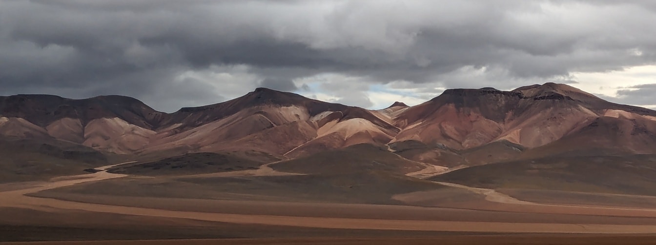 Pemandangan gurun Salvador Dalì di Bolivia dengan pegunungan dan awan