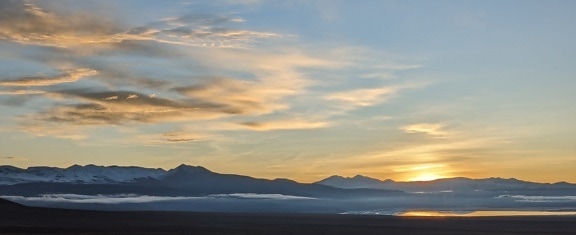Τοπίο με βουνά και σύννεφα κατά την ανατολή του ηλίου