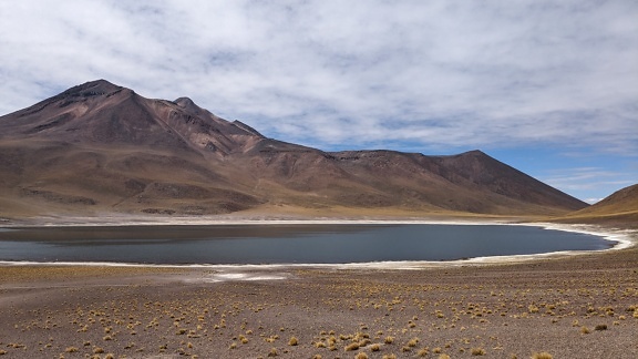 アタカマ砂漠の塩湖Laguna Miñiquesと背景に火山Miñiques
