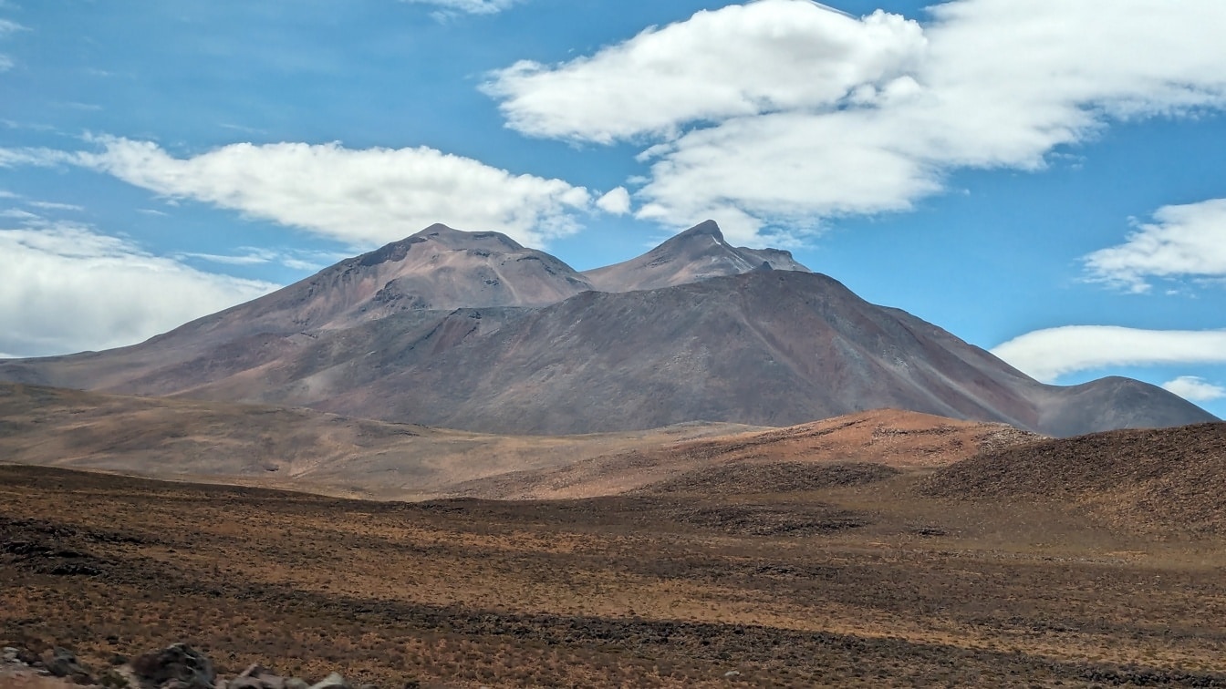 เทือกเขาในชิลีในทะเลทรายที่แห้งแล้งที่สุดในโลกพร้อมท้องฟ้าสีครามและเมฆ