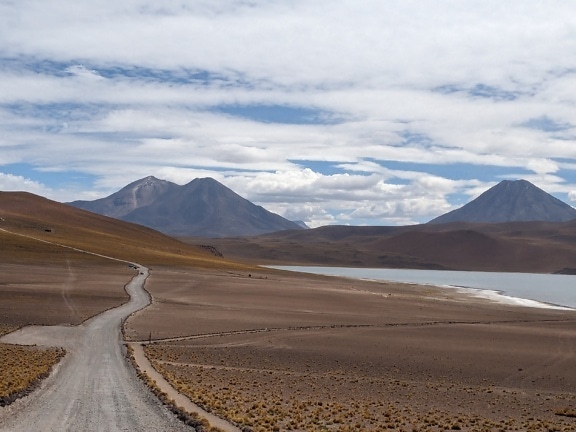 Road in Atacama desert in Chile leading to a lake