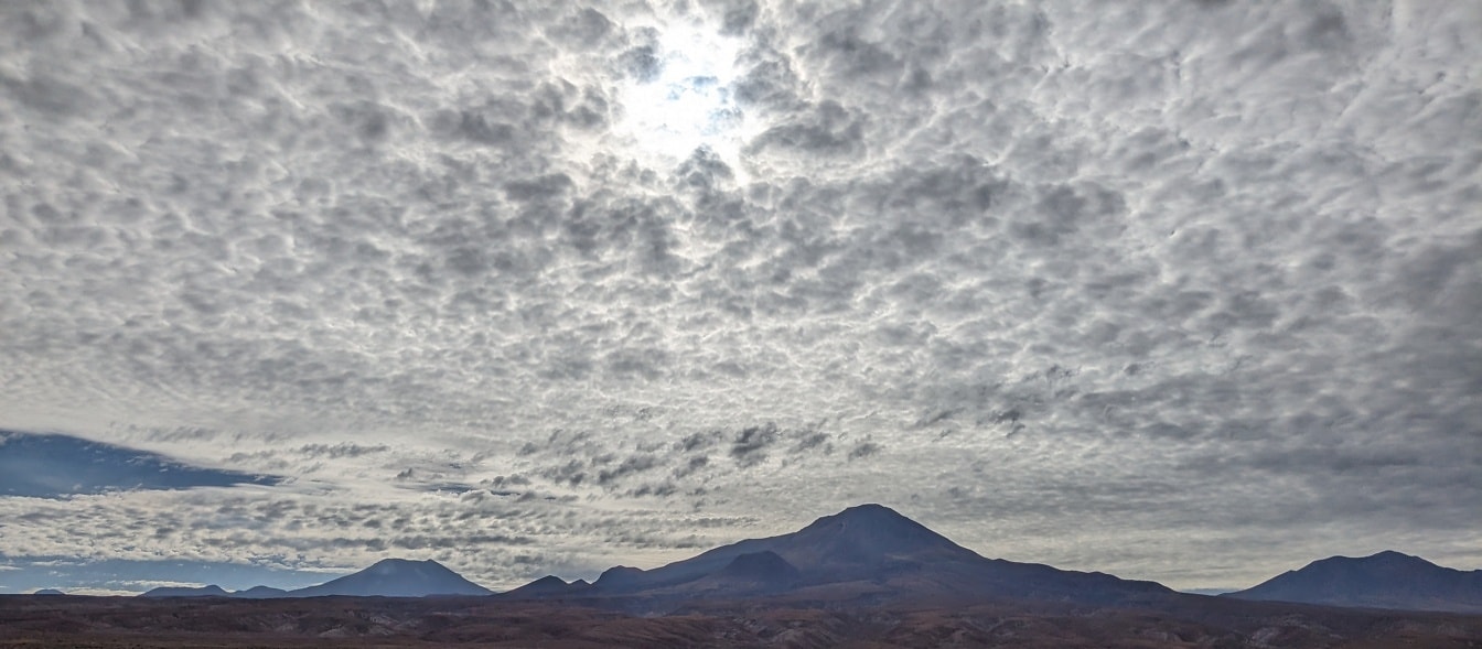 Munți în deșert cu nori pe cer
