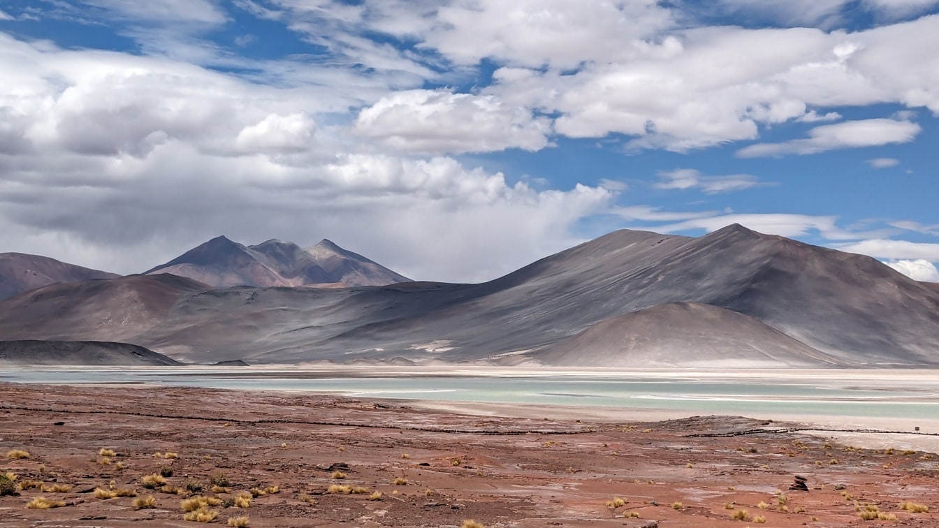 Pemandangan tepi danau yang luar biasa di dataran tinggi garam di gurun Atacama dengan pegunungan di kejauhan