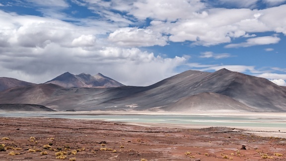ภูมิทัศน์ที่น่าทึ่งของริมทะเลสาบที่ราบสูงเกลือในทะเลทราย Atacama ที่มีภูเขาอยู่ไกล