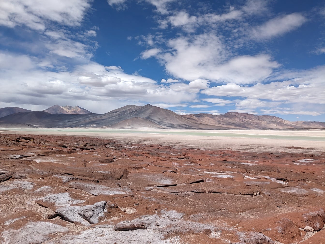 ดินแดนแห้งแล้งใน Piedras Rojas ในทะเลทราย Atacama ในชิลีโดยมีภูเขาเป็นฉากหลัง