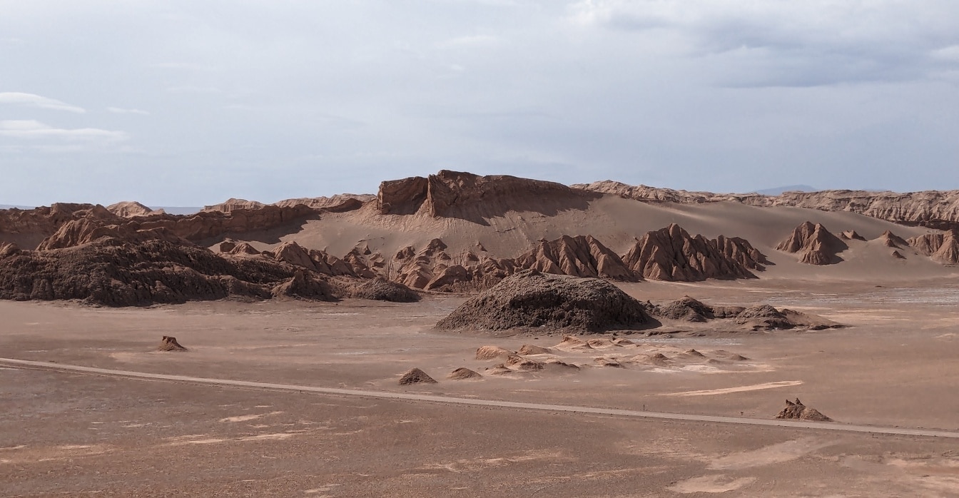 Staubige Straße in der Wüste mit Hügeln in einem Tal des Mondes in Chile