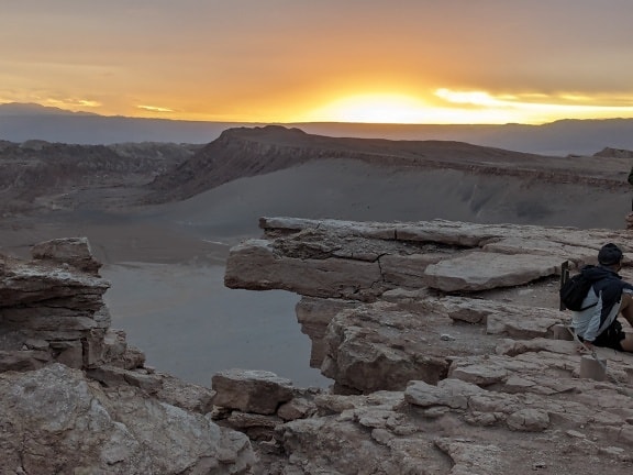 Ορειβάτης απολαμβάνει τοπίο στην Κοιλάδα του Φεγγαριού στη Βολιβία με ηλιοβασίλεμα