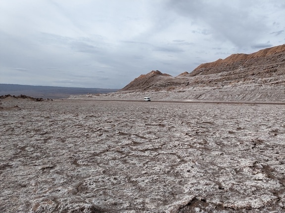 Car driving in a dry desert known as valley of the Moon in Chile