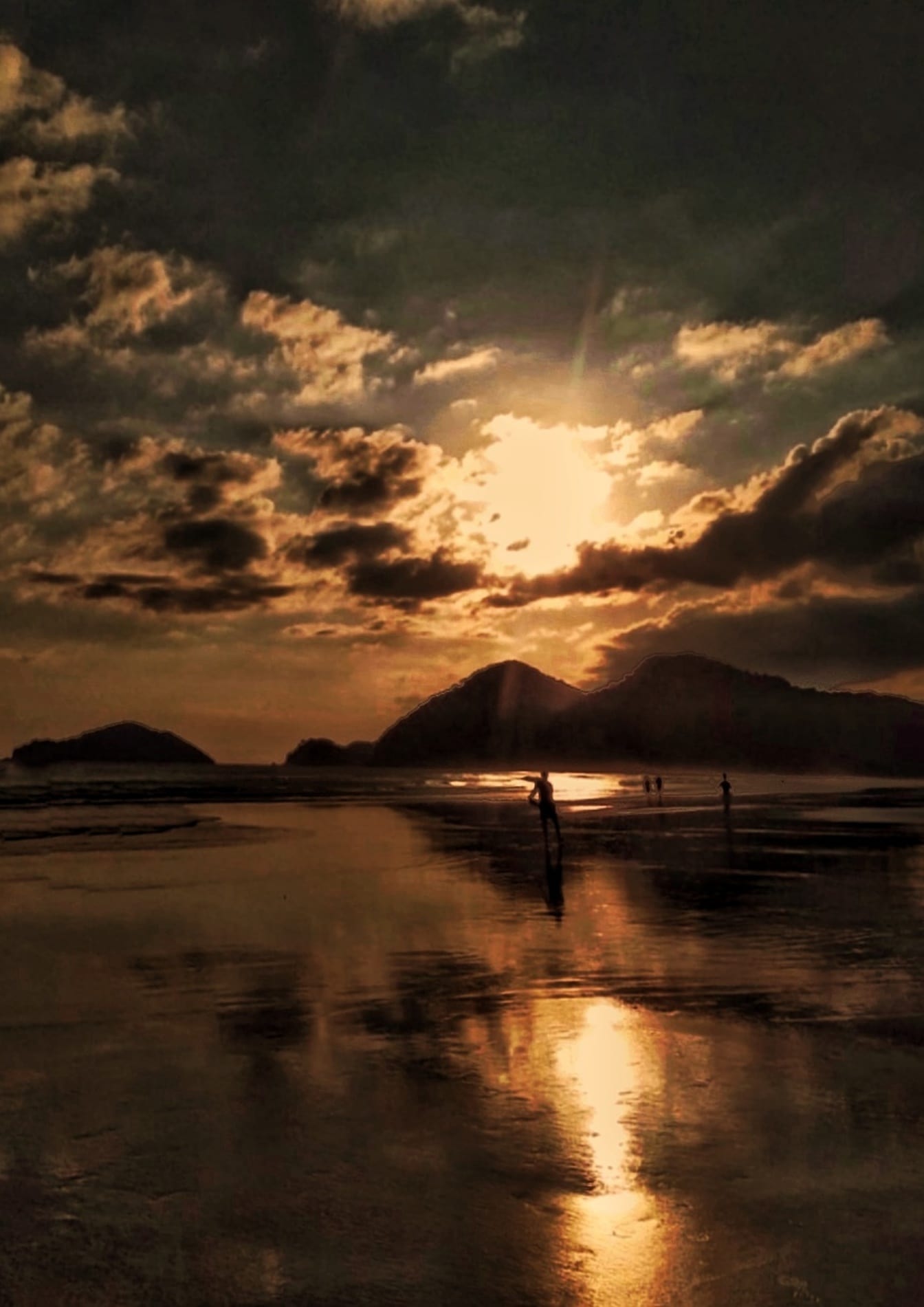 Silhuetter av människor som står på stranden i gryningen efter soluppgången