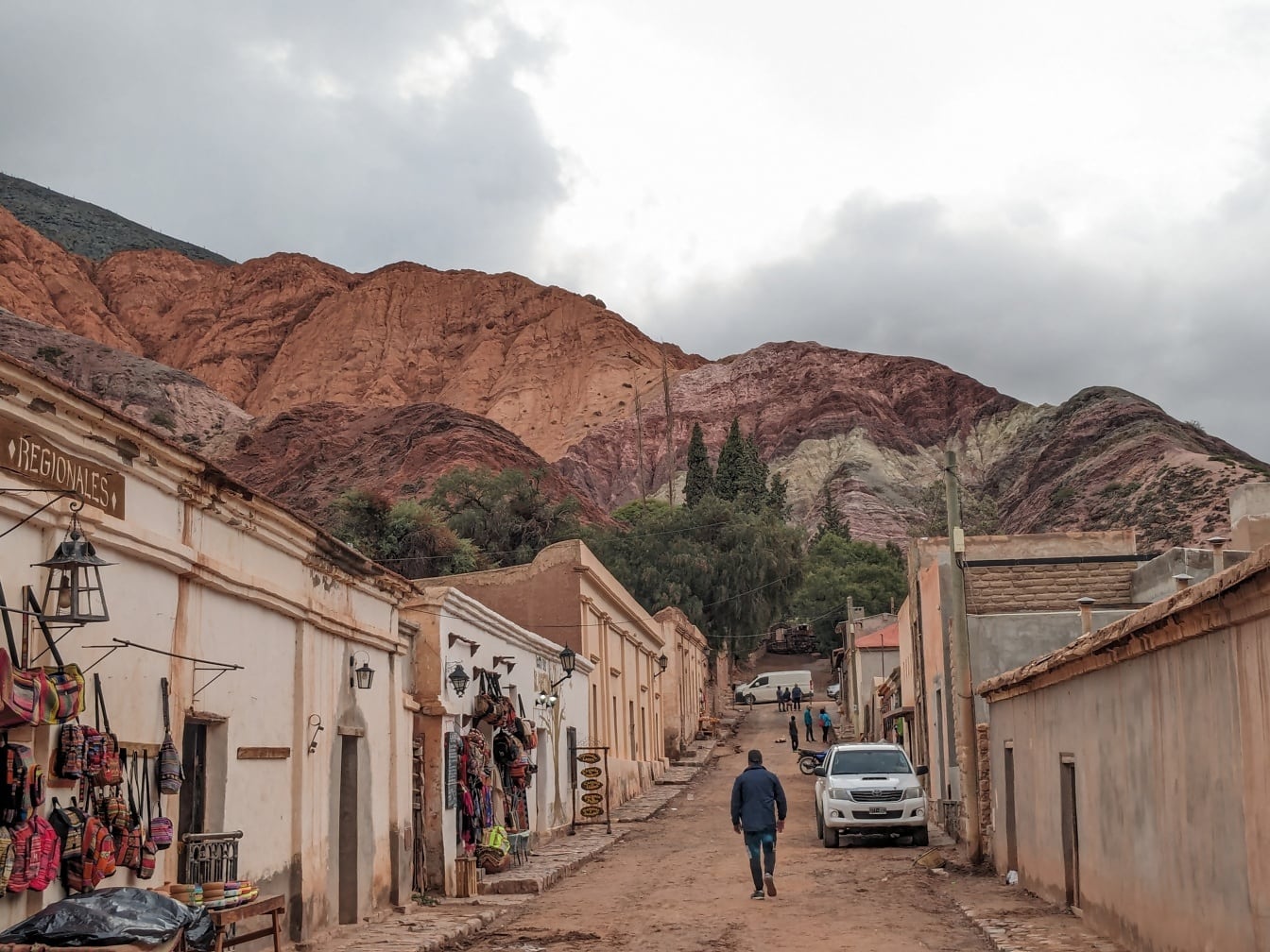 Landsbyboer som går nedover en jordvei i landsbyen Purmamarca i en dal med Andesfjellene i Argentina