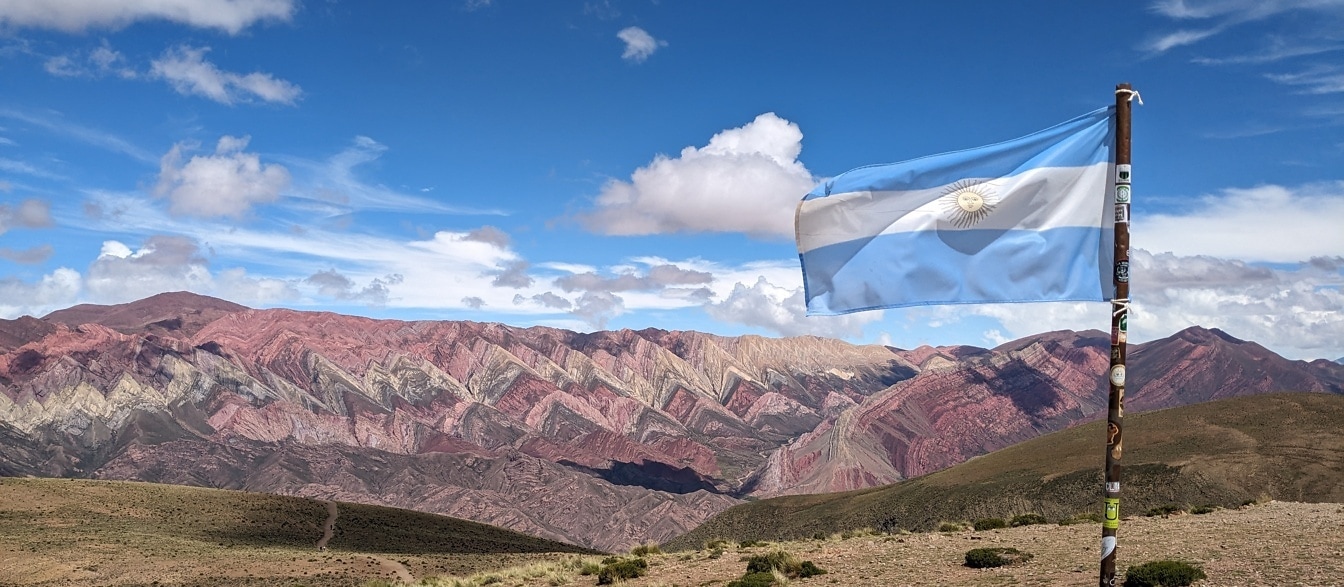 Flag of Argentina on rusty metal pole flying in the wind in mountainside