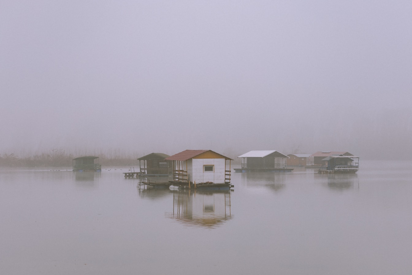 Zamlžené plovoucí domy na jezeře Tikvara u Dunaje ve městě Bačka Palanka v Srbsku