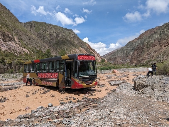 Туристичний автобус припаркований у скелястій місцевості в долині