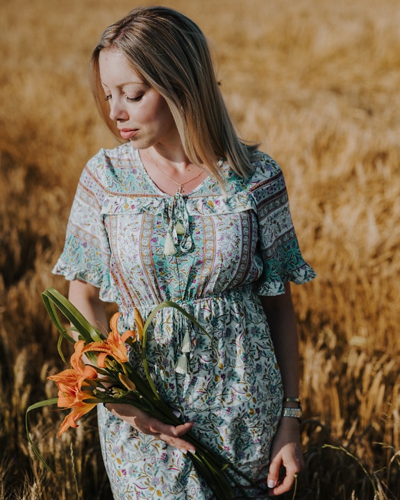 A country beauty in a folk dress holds flowers in a wheat field