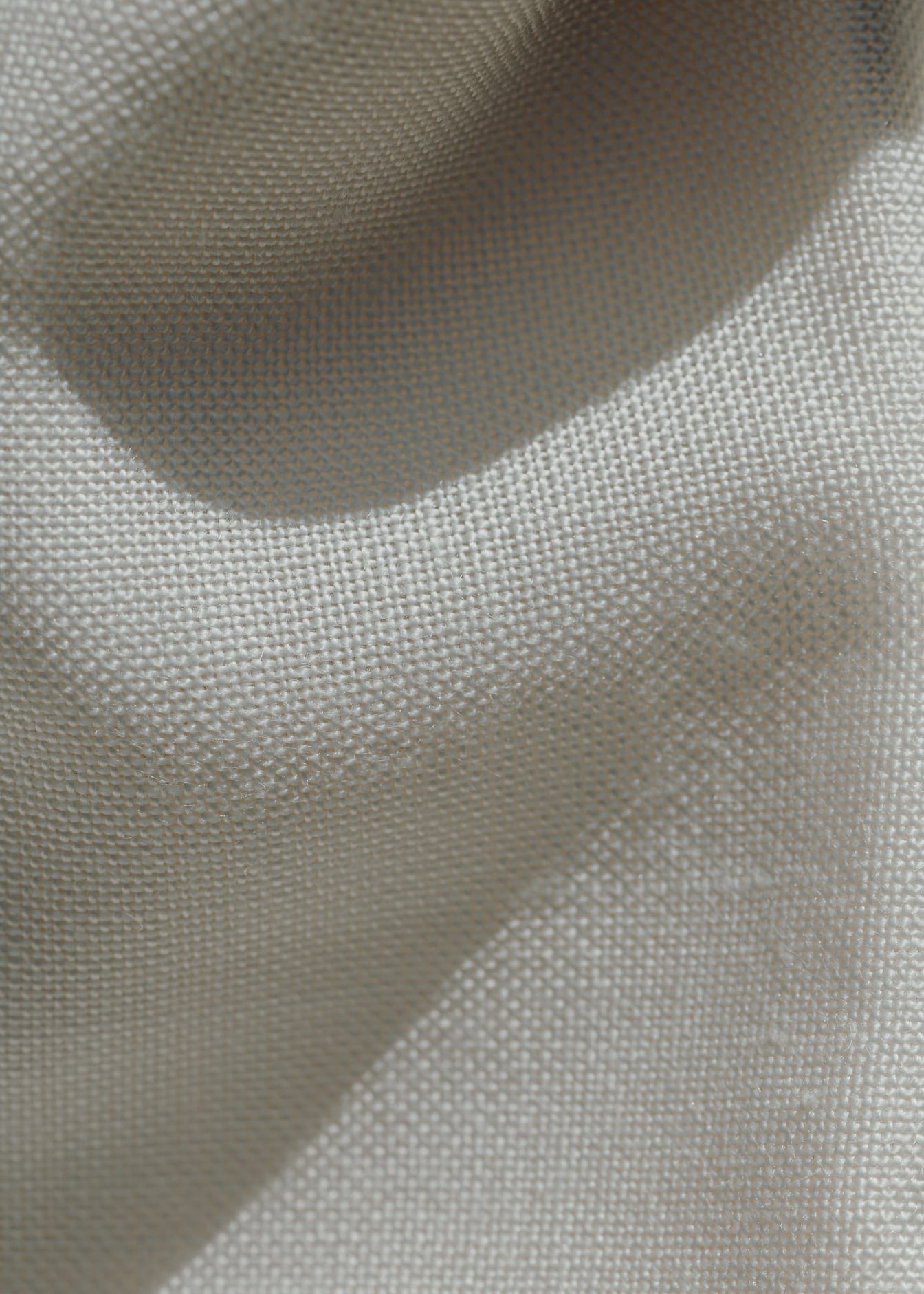 Close-up kain linen putih kusut dengan bayangan di atasnya