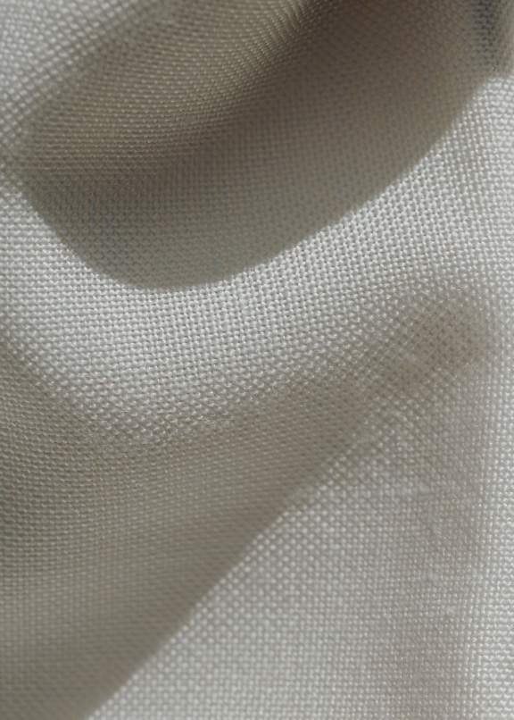 Close-up of a crumpled white linen fabric with shadows on it