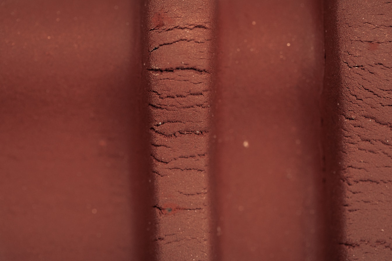 Nærbillede af en rød terracotta overflade med lodrette linjer