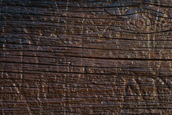 Surface of the old wooden plank painted with dark brown paint and transparent varnish