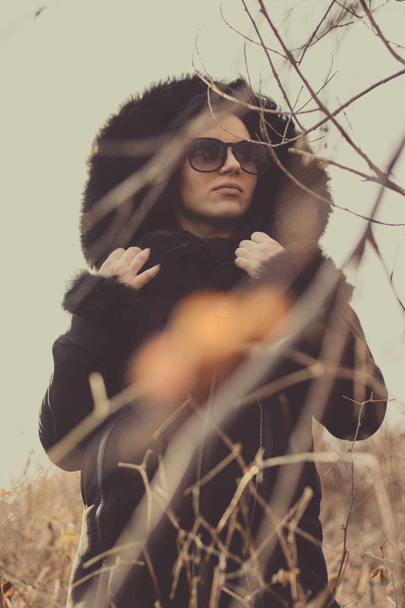 Portræt af en kvinde iført pelsjakke med hætte og solbriller