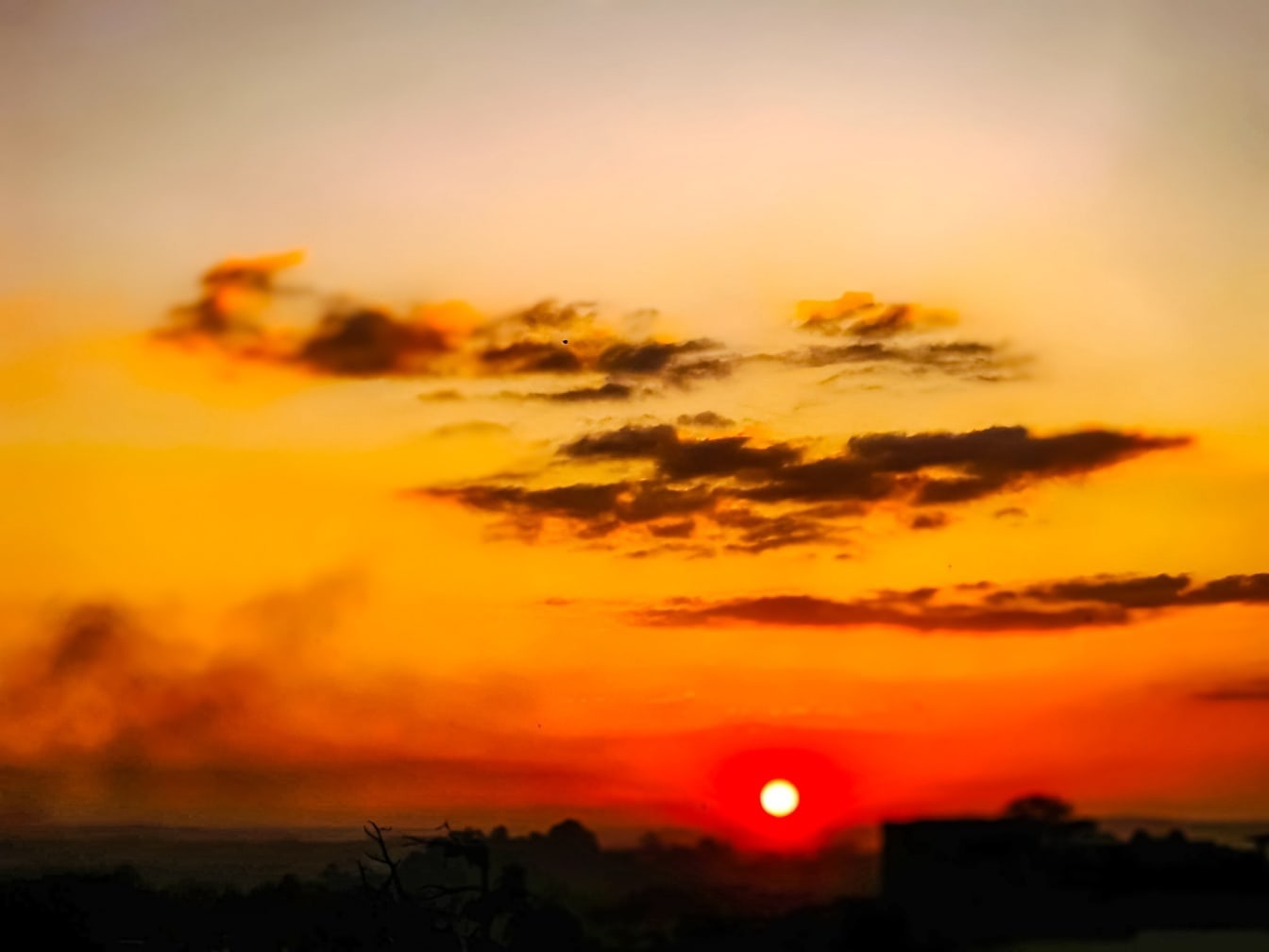 Disig orange himmel vid solnedgången med mörka moln
