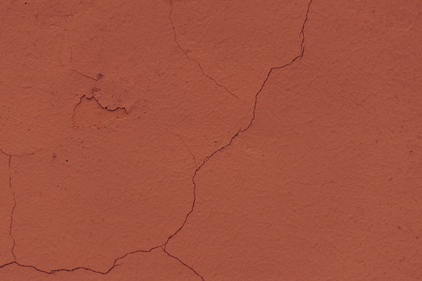 Antigua pared agrietada repintada con pintura marrón-rojiza