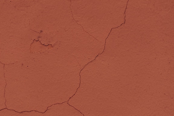 Old cracked wall repainted in brown-reddish paint