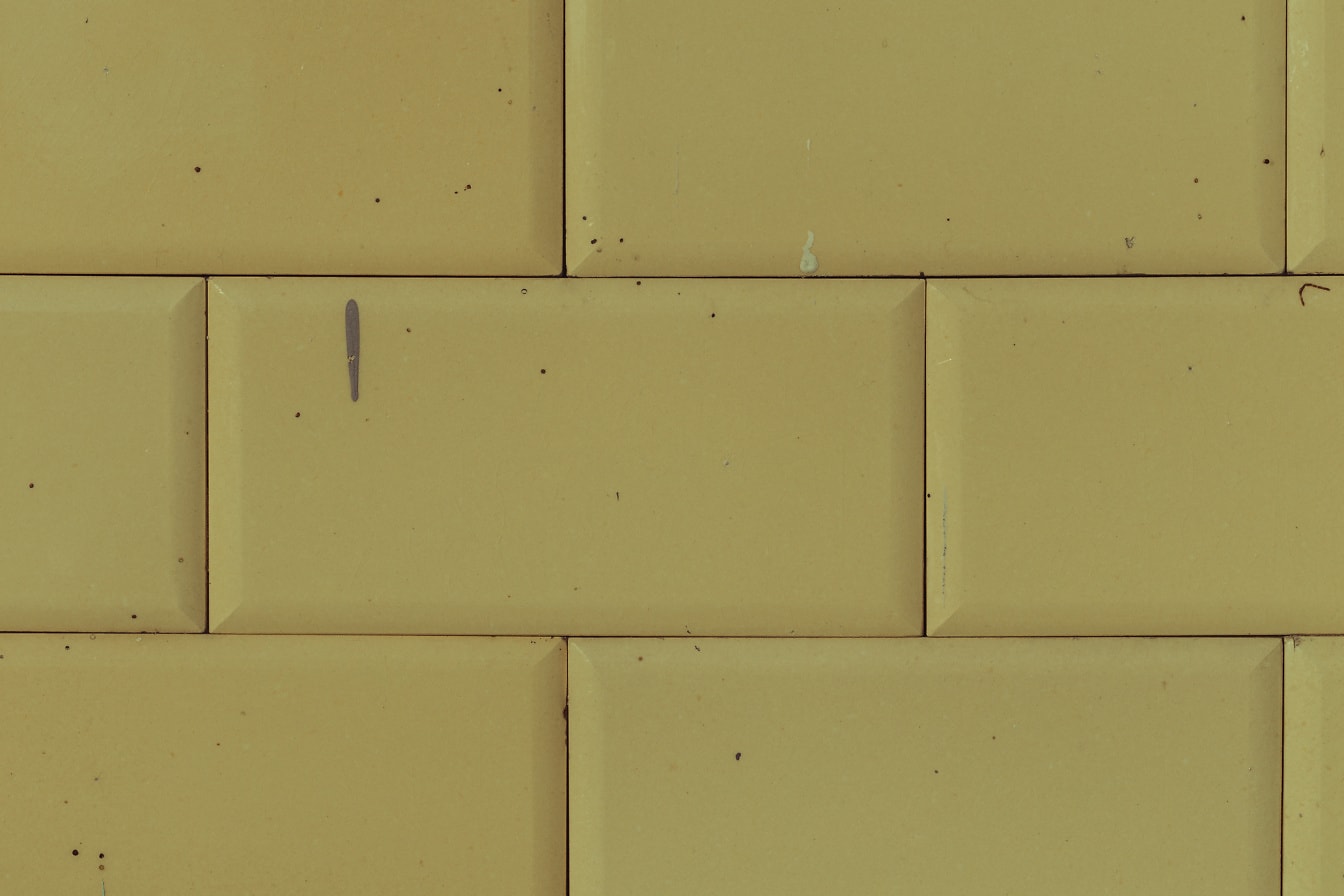 Tavalliset antiikkiset suorakaiteen muotoiset keltaiset seinälaatat tahroilla