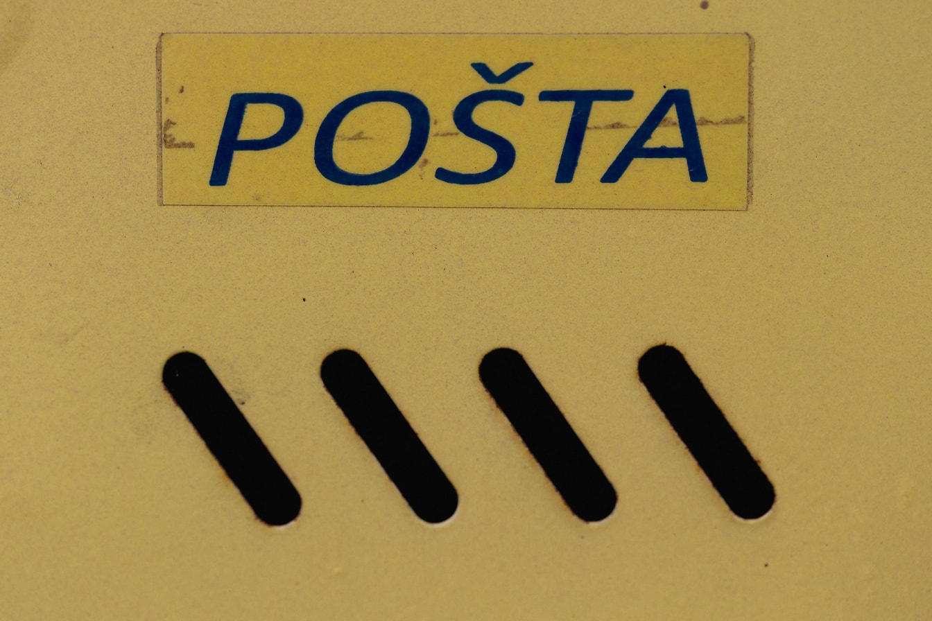 Gelber Briefkasten aus Metall mit blauer Aufschrift des Postamtes